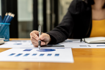 A business finance woman is reviewing a company's financial documents prepared by the Finance Department for a meeting with business partners. Concept of validating the accuracy of financial numbers.の写真素材