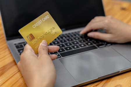 A woman typing on a laptop keyboard, she is filling out her credit card information to pay for an order on an Internet shopping site. Online shopping and credit card payment concept.の写真素材