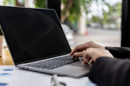 A business women working in a private room, She is typing on a laptop keyboard, She uses a messenger to chat with a partner. Concept of using technology in communication.の写真素材
