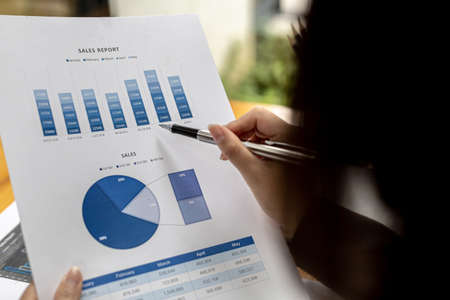 A business finance woman is reviewing a company's financial documents prepared by the Finance Department for a meeting with business partners. Concept of validating the accuracy of financial numbers.の写真素材