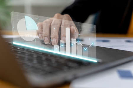 Close-up businesswoman hand using a laptop touchpad to open a financial report, a graphic showing...