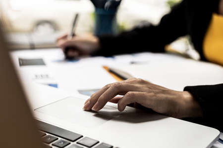 Close-up Person's hand using a laptop touchpad, a financial business woman working in the office and using a laptop to search for information and discuss business with partners. Technology concept.の写真素材