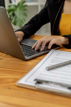 Business women calculate the amount on a housing estate sales document on a laptop, She is meeting...