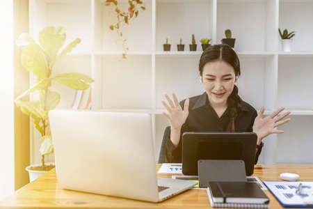 A beautiful Asian woman working in a private room, she is having a video conferencing with her supervisor and colleagues due to the company's work-from-home policy. The idea of working from home.の写真素材