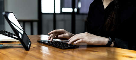 Hands of business woman typing on a tablet keyboard, she is using a messaging program to talk to a...