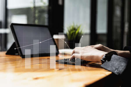 Person typing on tablet keyboard, bar chart graphs Line chart showing financial growth. Image of the concept of financial management and capital development for growth. Digital Finance.の写真素材