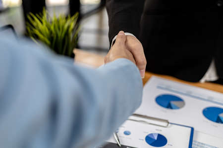 Close-up two business men holding hands, Two businessmen are agreeing on business together and shaking hands after a successful negotiation. Handshaking is a Western greeting or congratulation.の写真素材