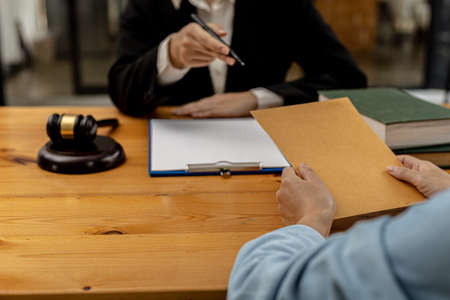 Attorneys are accepting documents from clients who come in to testify in case of embezzlement from business partners who venture into business. The concept of hiring a lawyer for legal proceedings.の写真素材
