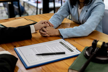 Lawyers shake hands to encourage clients who come to join the case of embezzlement from business partners who invest in doing business. The concept of hiring a lawyer for legal proceedings.の写真素材