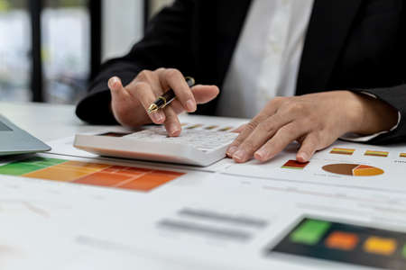 The company's finance manager is using a calculator, he uses a calculator to calculate the numbers in the company's financial documents that employees in the department create as meeting documents.の写真素材