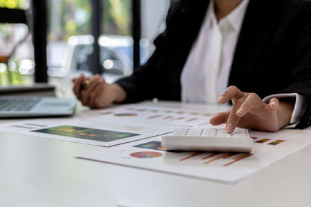 The company's finance manager is using a calculator, he uses a calculator to calculate the numbers in the company's financial documents that employees in the department create as meeting documents.の写真素材