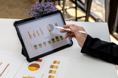 A woman looking at a tablet at a screen showing company financial status chart and presses a...