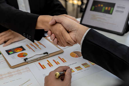 Close-up two business men holding hands, Two businessmen are agreeing on business together and shaking hands after a successful negotiation. Handshaking is a Western greeting or congratulation.の写真素材