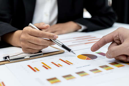 Two people pointing to a company financial summary, two businessmen brainstorming ideas to resolve losses and planning strategies to keep the company profitable and growing.の写真素材