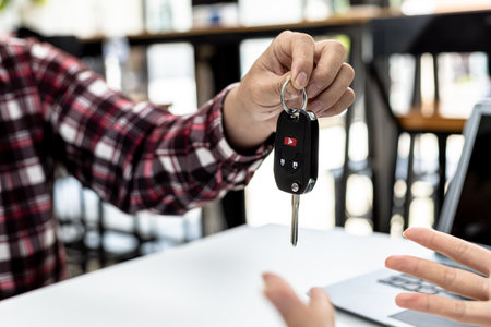 Person holding the car key to the car rental company employee, the customer who has completed the...