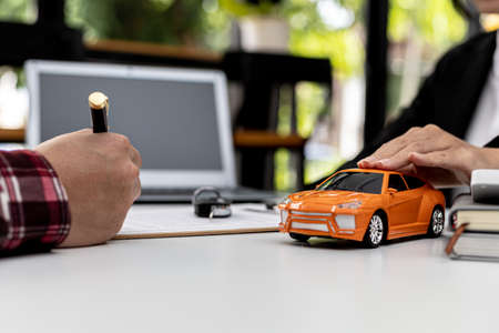 The renter is signing a car rental agreement with the car rental company. After discussing the...