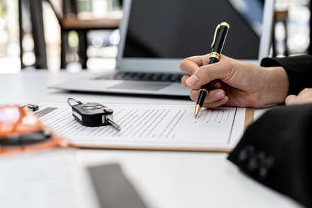 Car rental company employees are checking the contract before sending the car to the customer to rent the car, preparing the contract for the customer to sign the rental agreement. Car rental concept.の写真素材