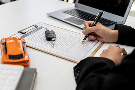 Car rental company employees are checking the contract before sending the car to the customer to rent the car, preparing the contract for the customer to sign the rental agreement. Car rental concept.の写真素材