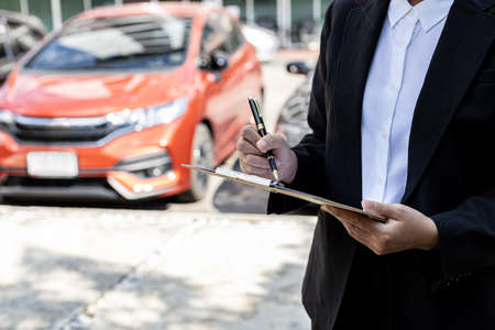 A person holding a file, a female employee of a car rental company is about to deliver the car to a customer who has signed a rental contract and paid the deposit. Car rental concept.の写真素材