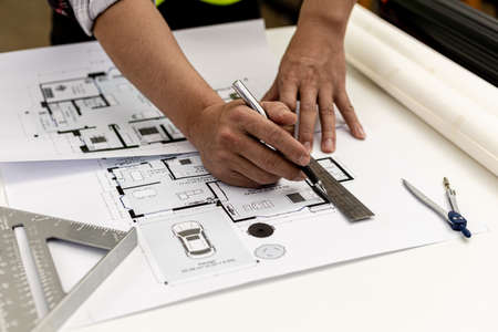 Architect uses a ruler to measure the blueprints of the houses he designed, designing the buildings according to the standards and the law, designing the houses according to the needs of the residentsの写真素材