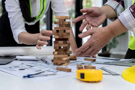 Engineers and architects are playing on wooden game condos on top of desks, comparing playing wooden games to standardized and beautiful building designs. Interior design ideas.の写真素材