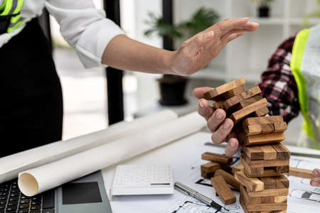 Engineers and architects are playing on wooden game condos on top of desks, comparing playing wooden games to standardized and beautiful building designs. Interior design ideas.の写真素材