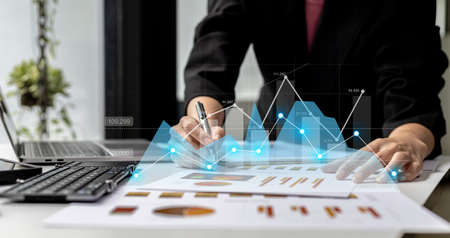 A businesswoman examines data on financial documents, company financial reports, graphics showing...