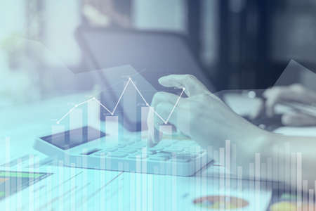 Businesswoman presses a calculator to check data on documents, company financial reports, graphics showing financial and numerical growth data. Financial management to grow and be a profitable conceptの写真素材