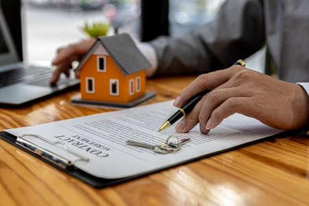 A salesperson of a housing project is drafting a sales contract for a customer who reserves a house in the project he manages. Real estate trading concept.の写真素材