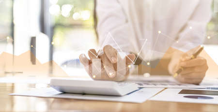 Businesswoman presses a calculator to check data on documents, company financial reports, graphics showing financial and numerical growth data. Financial management to grow and be a profitable conceptの写真素材