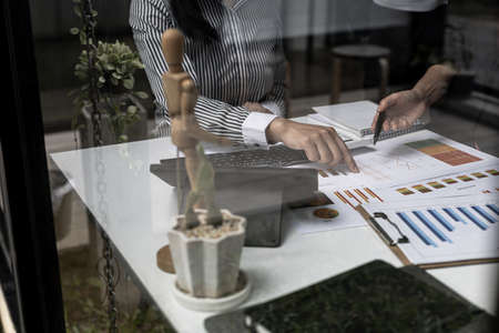 Close-up photo of two businessmen pointing at a sales data sheet in graph format, they are meeting...
