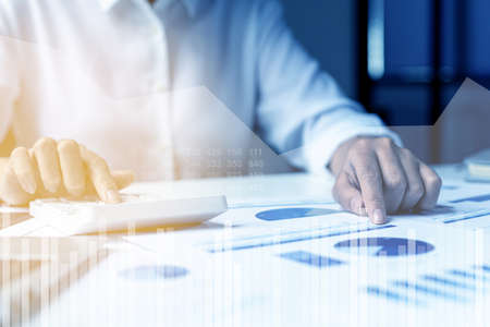 A business man examines data on financial documents, company financial reports, graphics showing...
