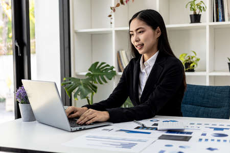 Businesswoman viewing financial data on laptop, she is reviewing financial data to bring to meetings with business partners. Concept of company financial management. Checking financial information.の写真素材