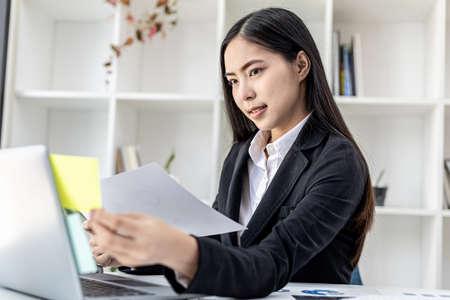 Woman working in a private office, a business woman owner of a company holding a notepad with notes...