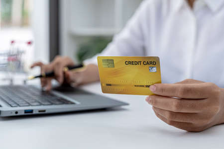 Woman holding credit card and typing on a laptop keyboard, she is filling out credit card information to pay for an order on an internet shopping site. Online shopping and credit card payment conceptの写真素材