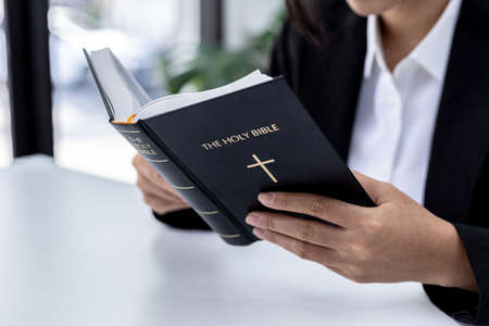 A person is reading the Bible, he is praying to the Bible, he is reading and studying the Bible. Concept of Christianity and Bible Study.の写真素材