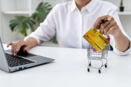 Woman holding credit card and typing on a laptop keyboard, she is filling out credit card information to pay for an order on an internet shopping site. Online shopping and credit card payment conceptの写真素材