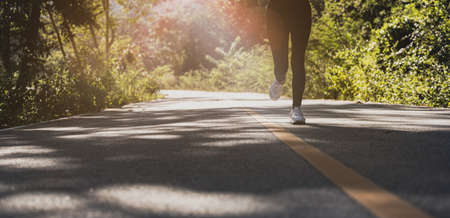 A woman is jogging on a park road, she is running in a park where a lot of people come for morning and evening jogging, running is a popular activity. Health care concept with jogging.の写真素材