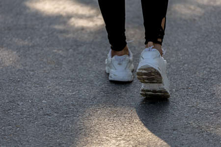 A woman is walking to warm up before jogging, she is running in a park where many people come to jogging in the morning and evening, running is a popular activity. Health care concept with jogging.の写真素材