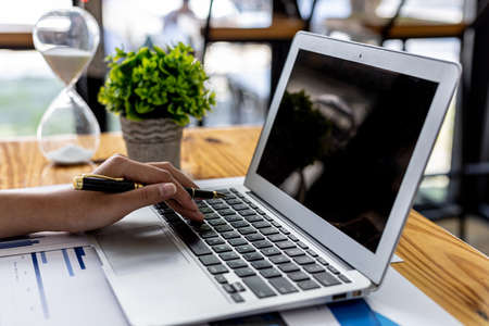 A business women working in a private room, She is typing on a laptop keyboard, She uses a messenger to chat with a partner. Concept of using technology in communication.の写真素材