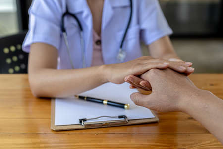 The doctor shakes hands to encourage the patient after the diagnosis results are finished, the patient detected a serious disease in the early stages. Concept of disease diagnosis.の写真素材