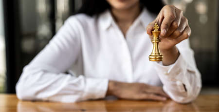 Person playing chess board game, business woman concept image holding chess pieces like business competition and risk management, planning business strategies to defeat business competitors.の写真素材