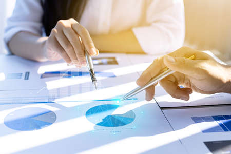Two businessmen are meeting together, they point to financial documents to discuss plans and...
