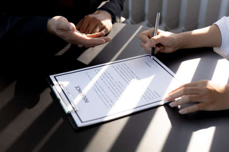 The home insurance salesman and the customer are signing an insurance agreement with their insurance company, accepting the terms and benefits. Home and real estate insurance concept.の写真素材