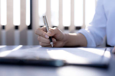 The home insurance salesman and the customer are signing an insurance agreement with their insurance company, accepting the terms and benefits. Home and real estate insurance concept.の写真素材