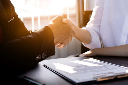 An insurance salesperson and a customer shake hands after signing an insurance contract with his insurance company. Home and real estate insurance concept.の写真素材