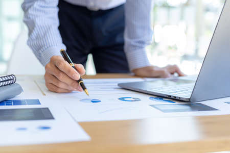 Businessman holding financial documents, he owns a startup company, he sits checking the company's...