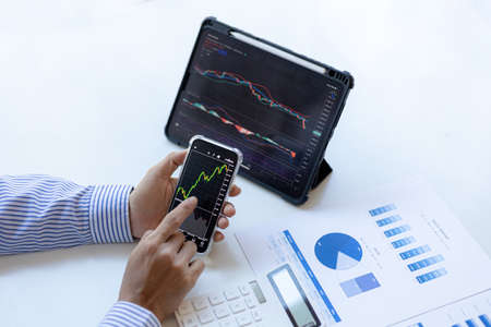 An investor is looking at stock charts on mobile phones and tablets, he is a stock investor, he...