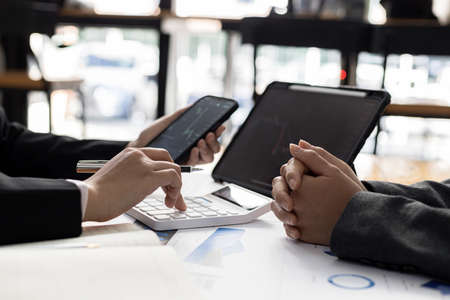 Two stock investors are brainstorming stock trading plans and reading stock market analysis,...