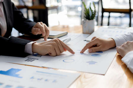 Two businessmen are reviewing the earnings summary and company financial documents that each...